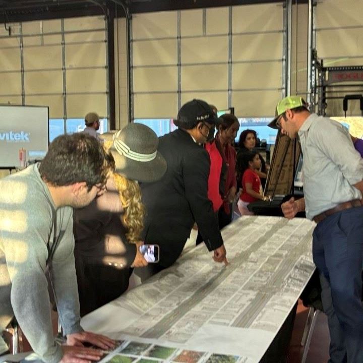 Group of community residents gathered around the table with the roll plot of the Broadway Corridor.